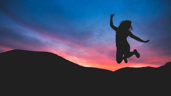 Person jumping in air with sun setting in the background