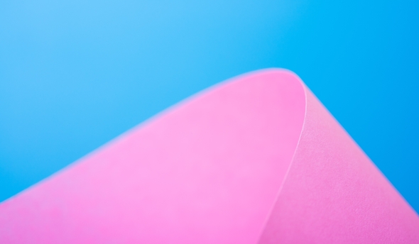 Pink paper curled against a blue background