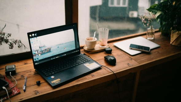 Laptop on a wooden desk by a window